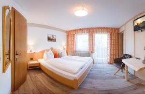 トゥクスにあるHaus Martinaの大きなベッドとデスクが備わるホテルルームです。