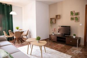 sala de estar con sofá, TV y mesa en MRZ Rentals Jerez Estación en Jerez de la Frontera