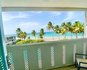 a balcony with a view of the beach and palm trees at KASA Brisa Marina - 1 bed 1 bath for 2 OCEAN VIEW BALCONY BEACHFRONT CONDO POOL in San Juan