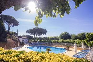 una piscina en un complejo con sillas y árboles en Camping Globo Barcelona, en Canet de Mar