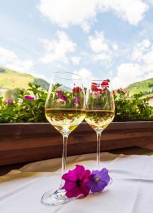 dos copas de vino sentadas en una mesa con flores en Haus Martina en Tux