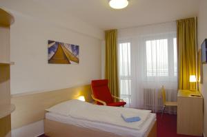 a hotel room with a bed and a red chair at Hotel Centrum Brno in Brno