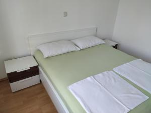 uma cama branca com lençóis brancos e almofadas em Apartment with private garden and terrace em Crikvenica