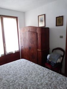 a bedroom with a bed and a chair and a window at Le Sapin 2 in Cogne