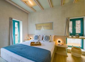 een slaapkamer met een groot bed met blauwe lakens en ramen bij Olvia in Chania