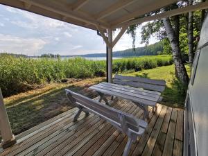 a wooden deck with a bench and an umbrella at Camp Pod Dębem in Ruciane-Nida