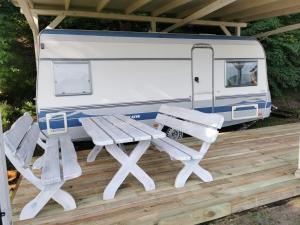 a picnic table and chairs on a deck with a camper at Camp Pod Dębem in Ruciane-Nida