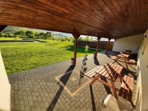 a porch with a wooden roof and benches on a patio at Kacsó Apartma in Ocna de Sus