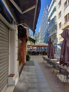 a sidewalk with tables and umbrellas on a building at Metropolis Apartments in Zagreb