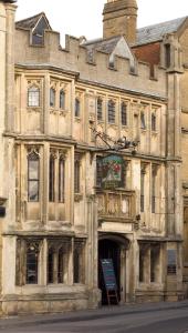 un vieux bâtiment avec un panneau devant lui dans l'établissement George & Pilgrims Hotel, à Glastonbury