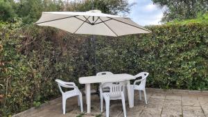 un tavolo bianco con due sedie e un ombrellone di Alloggio Turistico IL Bucchero a Porto Clementino