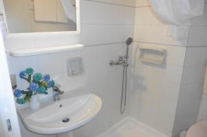 a white bathroom with a sink and a shower at Julies Apartments in Kokkini Khanion