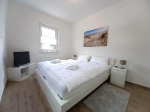 Habitación blanca con cama y TV en Ferienhaus Piel - Am Inselwald en Ueckeritz
