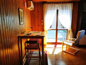 Habitación con escritorio, sillas y ventana. en MERIKOTKA - a cozy wooden cottage, sLOVEnia, en Braslovče