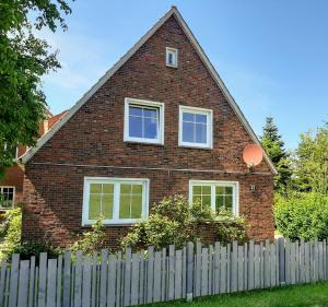 a red brick house with a white fence at Backbord in Wangerland