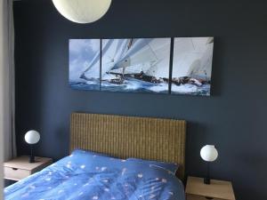a bedroom with a bed with two sailboats on the wall at Le Cézembre - vue 180 baie St Malo in Saint Malo