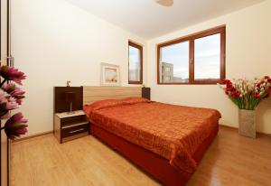 a bedroom with a bed and a vase of flowers at Stanny Court ApartHotel in Nesebar +14 photos