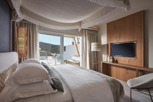a bedroom with a large bed and a television at Palladium Hotel in Platis Yialos Mykonos