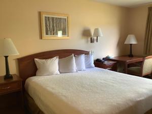 a hotel room with a bed with white sheets and pillows at Luxury Inn & Suites in Silverthorne