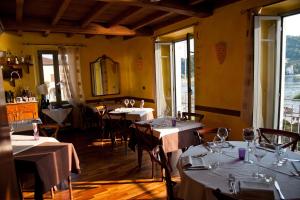 a restaurant with tables and chairs with white tablecloths at Foresteria Hostaria Del Golfo cod struttura C00025 in Laveno-Mombello +27 photos