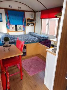 Cette petite chambre comprend deux lits et une table. dans l'établissement B&B boerderij rust, in pipowagens!, à Le Helder