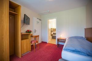 a bedroom with a bed and a desk and a table at Hotel Friedenseiche in Benediktbeuern