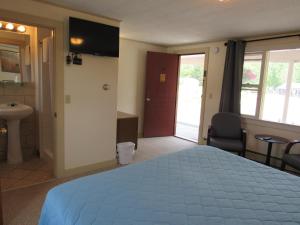 a bedroom with a bed and a bathroom with a sink at Acadia Gateway Motel in Trenton