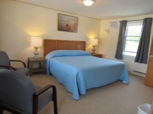 ein Schlafzimmer mit einem blauen Bett und einem Fenster in der Unterkunft Acadia Gateway Motel in Trenton