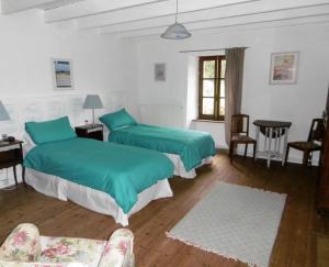 two beds in a room with green sheets at La Bicyclette Bleue in Montpinchon