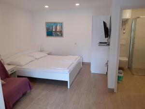 een witte slaapkamer met een bed en een televisie bij Apartments Haracic in Hvar