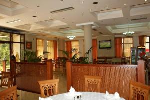 Hotel Colombo Elbasan في إلباسان: غرفة طعام بها طاولات وكراسي وتلفزيون