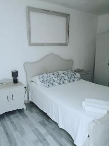 アルメリアにあるLinda casa pintoresca (Centro Almería)の白いベッドと壁の絵が備わるベッドルーム1室が備わります。