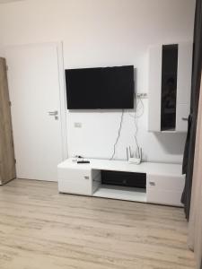 a white living room with a tv on a white wall at Mirror Lake Apartment in Mamaia