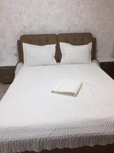 Una cama con sábanas blancas y un libro. en Mirror Lake Apartment, en Mamaia