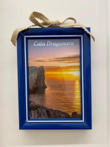 a picture of a beach in a blue frame on a wall at Le Calette 105 in Alghero