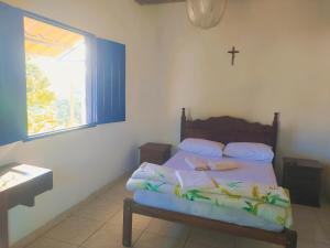una camera da letto con un letto con una croce sul muro di Hospedaria Villa Mariana a Santo Antônio do Leite Altre 28 foto