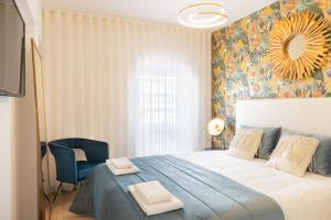 a bedroom with a large bed and a blue chair at Barra Apartament Design in Gafanha da Nazaré