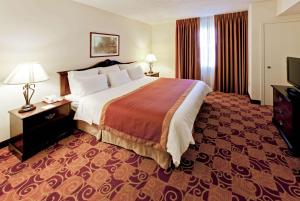a hotel room with a large bed and a television at Hawthorn Suites by Wyndham Louisville East in Louisville