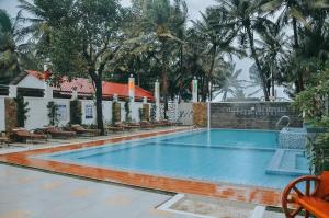 Villa MJ Maristela Beach Resort في Lemery: مسبح في منتجع فيه كراسي واشجار