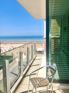 a chair sitting on a balcony looking at the beach at Luxury Suite Koksijde 310 - Adults only in Koksijde