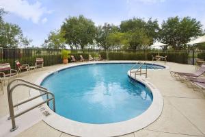 a large swimming pool with chairs and a fence at Ramada by Wyndham Suites Orlando Airport in Orlando