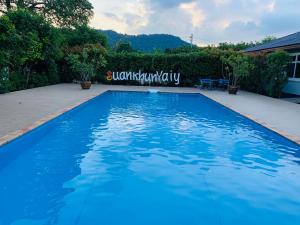 a large blue swimming pool in a yard at Baan Suan Khun Yaiy in Ban Wang Takhrai