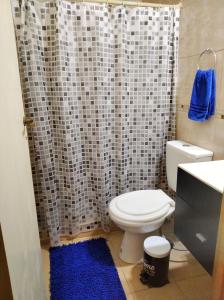 a bathroom with a toilet and a shower curtain at MG Suites in Monte Grande