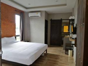 um quarto com uma grande cama branca e uma secretária em Bearry Loft em Nakhon Ratchasima