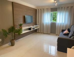 ein Wohnzimmer mit einem Sofa und einem TV in der Unterkunft Edifício Mariana Apto com 3 Quartos - Jatiúca in Maceió