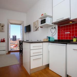 una cocina con armarios blancos y una pared roja en Apartamentos com Historia, en Coímbra