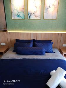 een slaapkamer met een blauw bed met drie foto's aan de muur bij Imperio Residence City View in Melaka