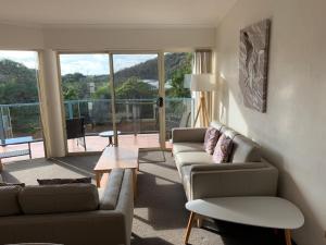 una sala de estar con sofás y vistas a un balcón. en BlueWater Apartments en Merimbula