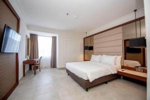 Dormitorio con cama, escritorio y TV en Mahkota Hotel Singkawang en Singkawang