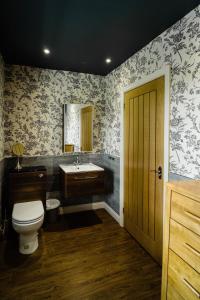 een badkamer met een toilet, een wastafel en een spiegel bij The Rectory Rooms, Studio 2 in Threshfield